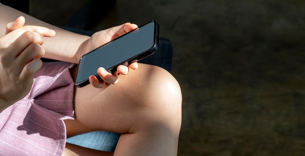 Young woman using smartphone while sitting at home, under the sunlight from window.