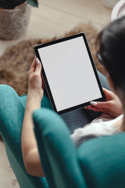 Young woman using a tablet while sitting in a comfortable chair top view