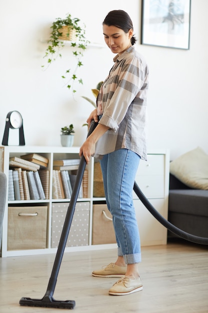 Young woman using vacuum cleaner for housework she vacuuming the floor at home