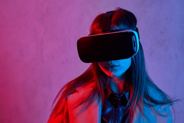 Young woman using virtual reality helmet while wearing a coat