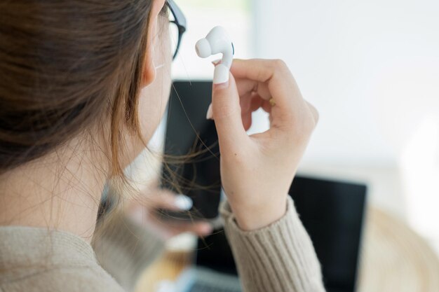 Young woman using wireless headphone listening to music with her smartphone.