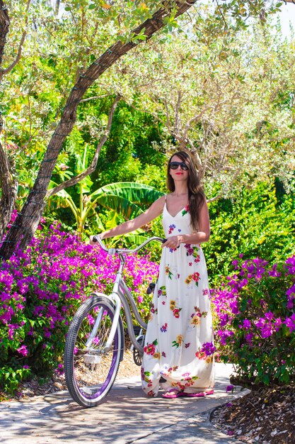 花の咲く庭園で自転車に乗って休暇中の若い女性