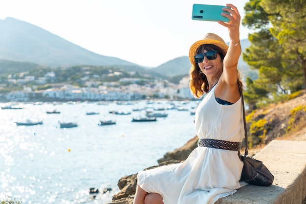 A young woman on vacation taking a selfie in Cadaques by the sea, Costa Brava de Catalunya, Gerona, Mediterraneo. Spain