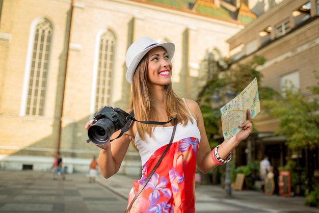 Giovane donna in vacanza che cammina e studia la mappa della città.