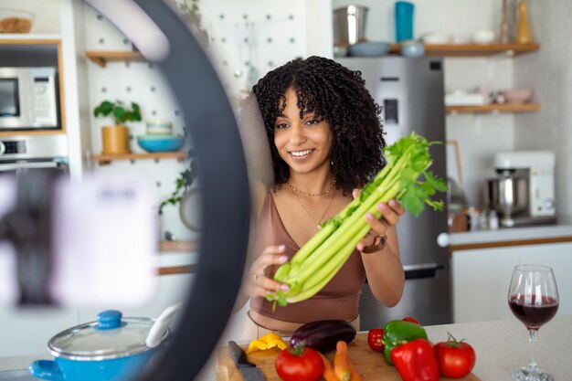 Young woman videoblogger cooking at the kitchen and filming African American woman vlogger baking and recording video for food channel