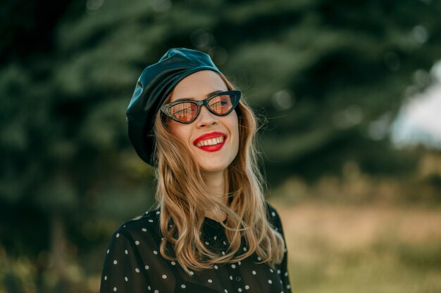 Young woman in vintage black polka dot dress posing outside