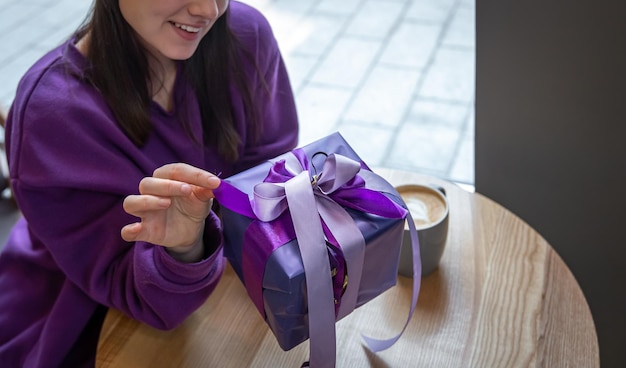 A young woman in violet sweater with purple gift box