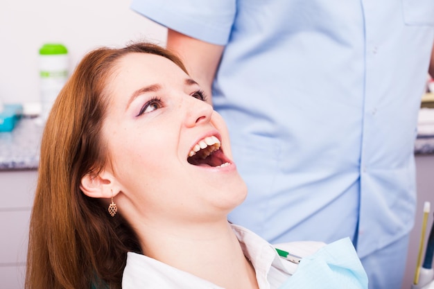 若い女性が歯科医を訪問し、顔をクローズアップ