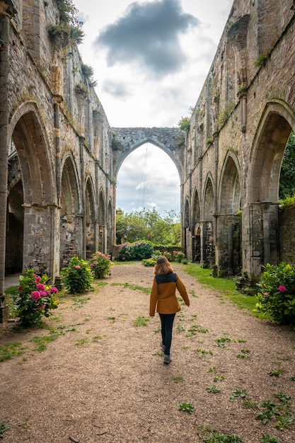 Photo a young woman visiting the ruins of the abbaye de beauport church in the village of paimpol, cãâ´tes-d'armor department, french brittany. france