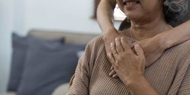 A young woman a volunteer a son carefully hugs his beloved\
grandmother supports and helps an elderly woman in retirement his\
grandparent young male and female elderly hands with wrinkles\
closeup