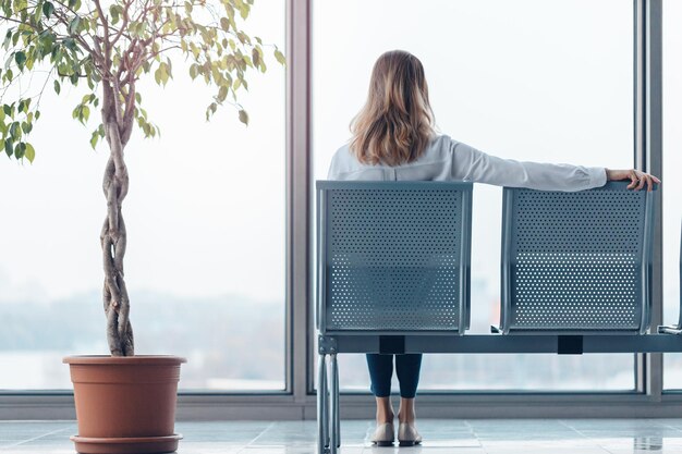 Young woman waiting for a flight in a modern airport lounge