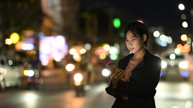 A young woman waits for her private taxi while using a transportation app on mobile