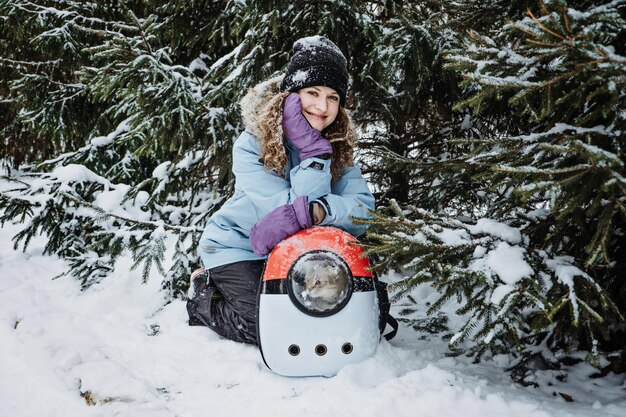 Young woman walk with cat in pet carrier backpack in winter park forest bubble backpack carrier for