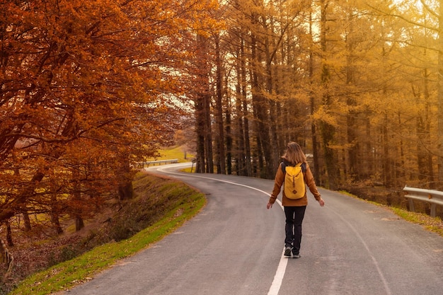 A young woman walking alone in solitude on a road in Autumn