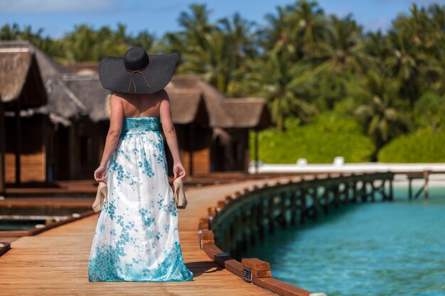 Young woman walking along the bridge with black hat