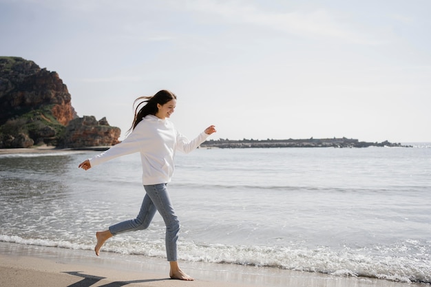 Foto giovane donna che cammina sulla spiaggia di sabbia