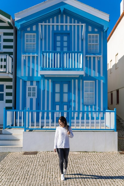 Young woman walking in front of a typical blue and striped house