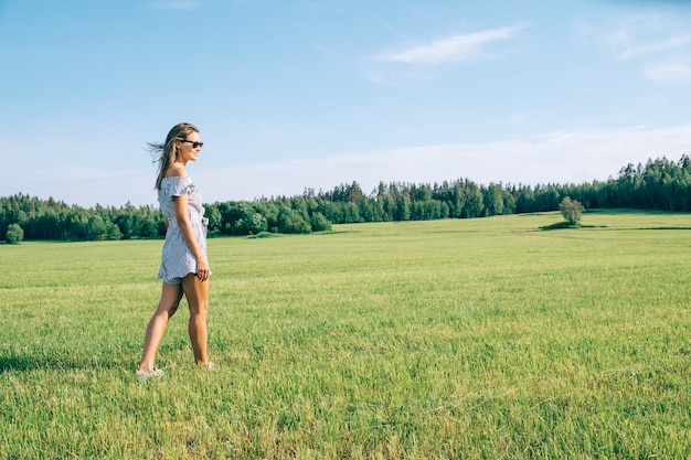 Young woman walking in the green sunny field