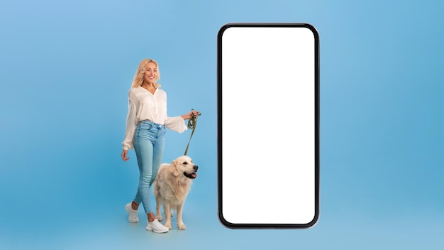 Young woman walking her dog near big smartphone