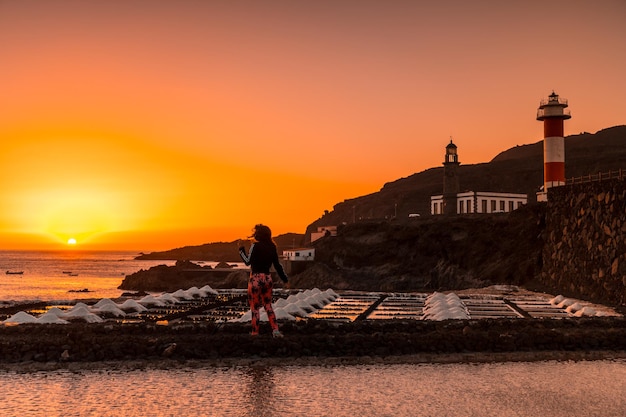 A young woman walking in the orange sunset in the salina and in the background