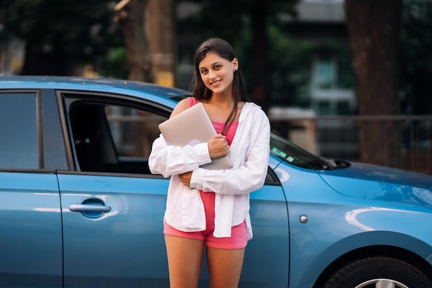 Young woman walking outdoors holding laptop computer