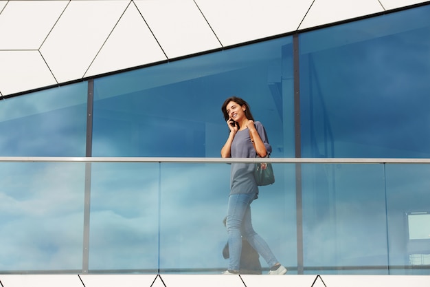 Young woman walking outdoors and talking on mobile phone