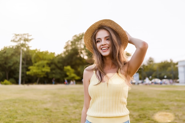 Young woman walking in the park and smiling in the summer sunset