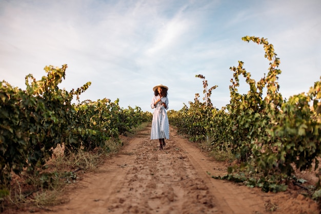 Young woman walking in a path in the middle of a vineyard