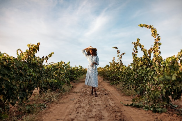 Young woman walking in a path in the middle of a vineyard