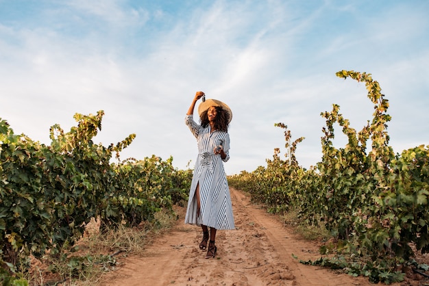 Young woman walking in a path in the middle of a vineyard