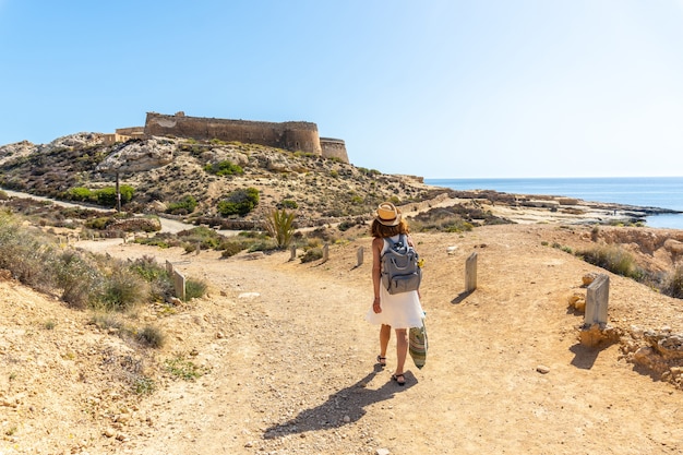 A young woman walking next to the Rodalquilar castle in Cabo de Gata on a beautiful summer day, AlmerÃ­a