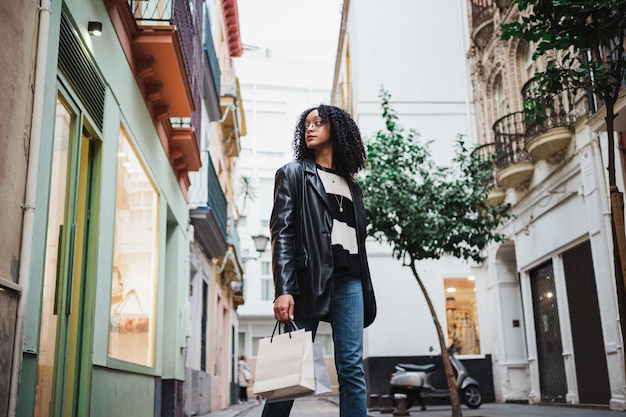 Young woman walking in the street while she is holding shopping bags