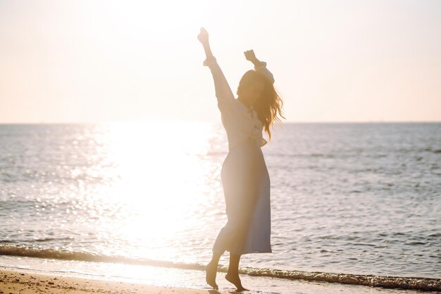 ビーチで夕日の中を歩く若い女性夏の時間旅行週末ライフ スタイル コンセプト