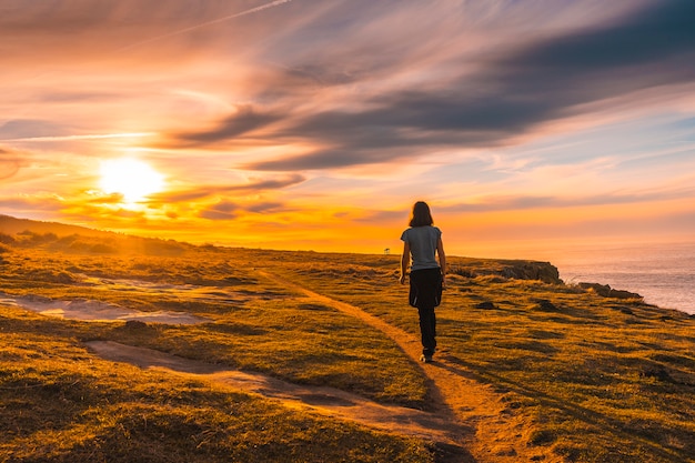 A young woman walking in the sunset of Jaizkibel. Basque Country