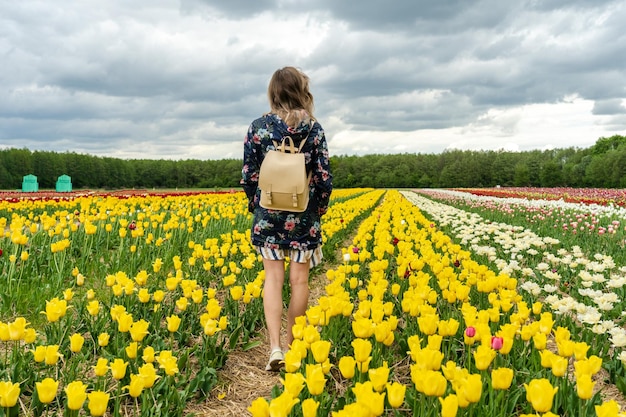 Young woman walking through beautiful colorful tulips field