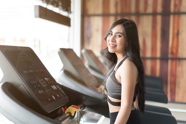 Giovane donna che cammina sul tapis roulant e in palestra