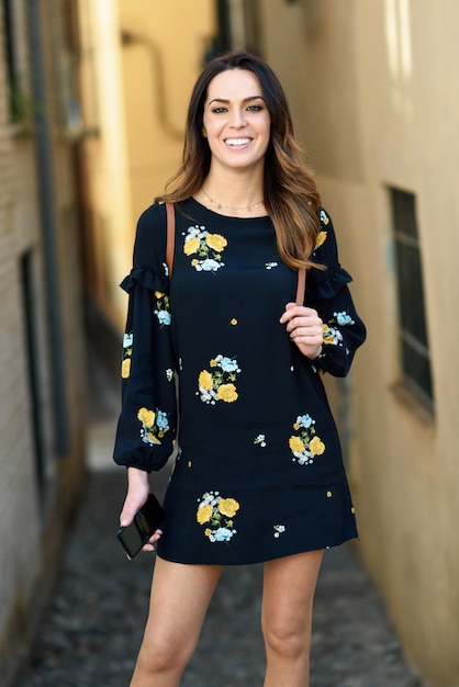 Young woman walking in urban background. Female in casual clothes with care hair.