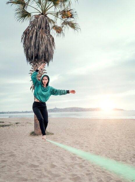 Young woman walking on the webbing slack lining at the beach