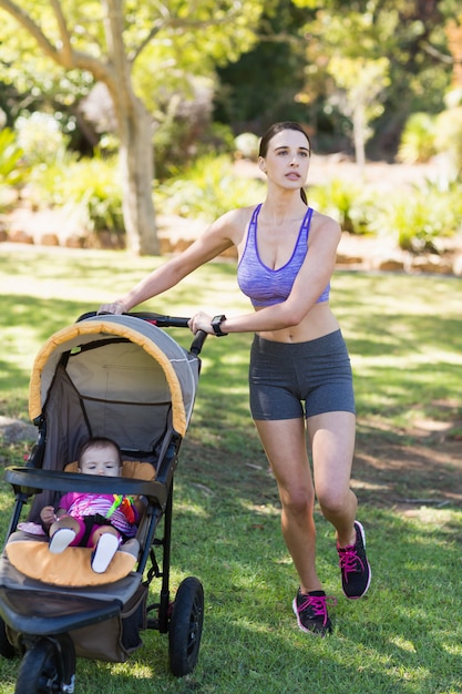 Photo young woman walking with baby stroller