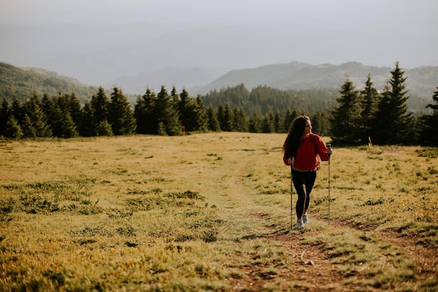 Young woman walking with backpack over green hills