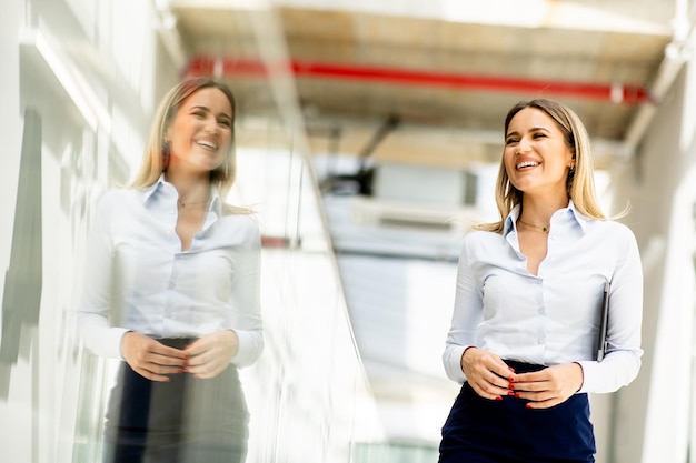 オフィスの廊下でデジタル タブレットを持って歩く若い女性