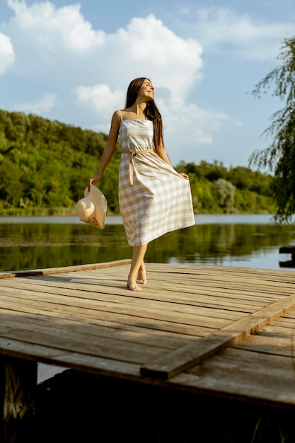 Foto giovane donna che cammina sul molo di legno al lago calmo