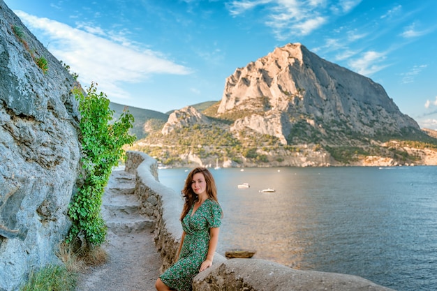 A young woman walks along the Golitsyn trail with a view of the mountains and the seascape i