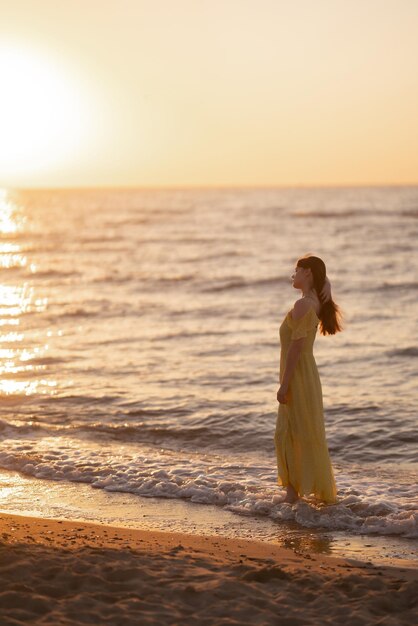 Young woman walks along seashore at sunset Nature relax lifestyle concept