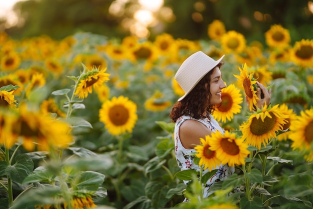 Young woman walks on blooming sunflower field Happiness with nature Summer holidays