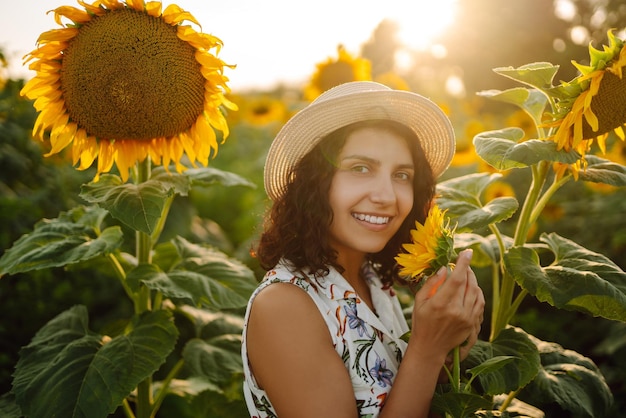 Young woman walks on blooming sunflower field Happiness with nature Summer holidays