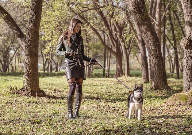 A young woman walks a dog in the park on a sunny October day