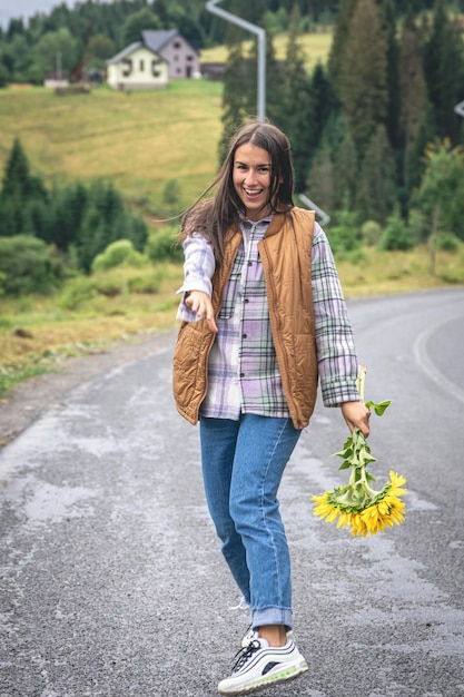 A young woman walks in the mountains with a bouquet of sunflowers