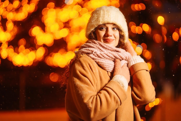 Young woman walks through the night winter city light around winter fashion holidays rest