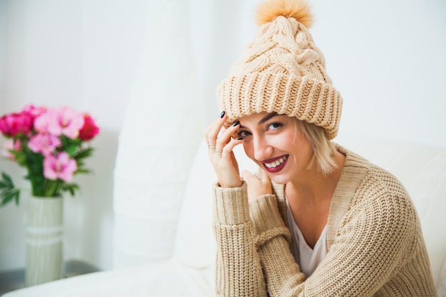 Giovane donna in cappello lavorato a maglia a mano beige caldo a casa